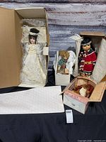 Group shot of all four boxed figures: bride doll, Native doll, Gund bear box, baby doll box