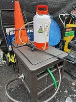 Overall shot showing hose reel cabinet with green hose and HDX pump sprayer on top