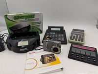 Group shot of all items: camera, charger, calculators, poker game, manual