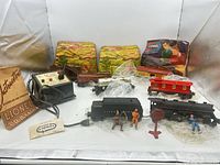 All train set components laid out including locomotive, cars, transformer, track, booklet, figures