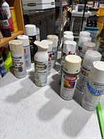 Group of spray paint cans on table showing brands and colors
