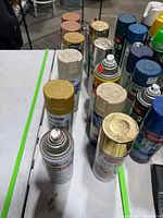 Front angled view showing two rows of assorted spray paint cans with yellow, tan, brown and metallic caps