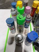 Top view of assorted spray paint cans showing brands, caps and usage levels