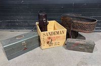 All five items grouped: Sandeman crate, wicker stair basket, two metal toolboxes, wine carrier