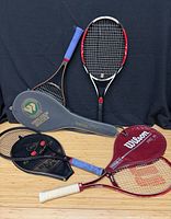 Group image of four tennis rackets and three covers
