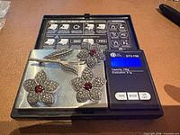 Front view of brooch and earrings on scale showing 32.6 g