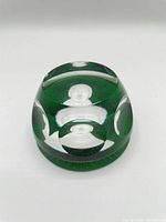 Angled view showing overall green glass paperweight with clear facets