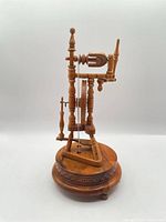 Side view of wooden spinning wheel music box on round base