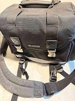 Front view showing Canon logo, front buckles, top handle and shoulder strap