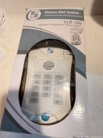 Front view of sealed retail box displaying LLR-100 distress alert system and accessories