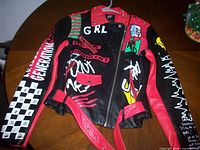 Front view of black and red faux leather jacket with graphics and studs