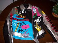 Front view of jacket showing multicolor graffiti design, silver sleeves, studded collar