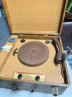 Record player inside open case showing platter, tonearm, control panel