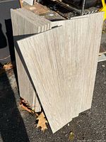Stack of light wood-grain porcelain tiles standing on edge outdoors