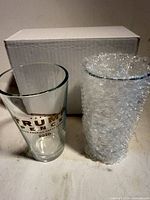 Two Trump Pence 2020 pint glasses, one wrapped in bubble, with box