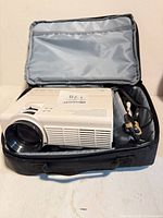 Projector inside open carrying case with cables visible
