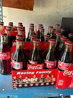 Multiple six-pack carriers of sealed Coca-Cola Racing Family glass bottles
