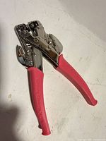 Full view of We R Memory Keepers Crop-A-Dile eyelet punch tool with pink handles