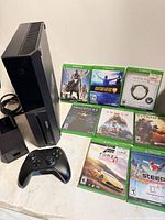 Front view of Xbox One console, eight Xbox One game cases, wireless controller