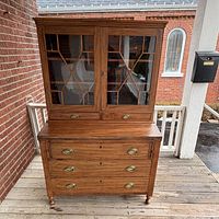 Full view of bookcase showing glazed upper doors, two small drawers, fall-front, and three graduated drawers