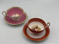 Both teacup and saucer sets displayed side by side to show patterns and condition