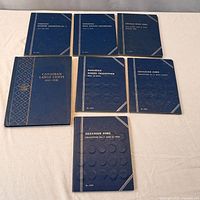 Seven blue Whitman coin folders closed