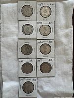 Fronts of nine Canadian 50-cent coins in flips, handwritten years visible