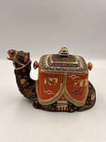 Left side view of camel-shaped teapot showing painted details and overall form