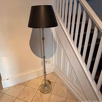 Full view of floor lamp showing chrome column, black shade, glass base