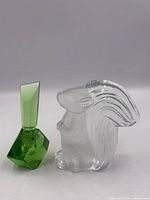 Green glass perfume bottle and clear glass squirrel side by side