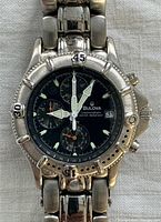 Close-up of watch dial and bezel showing chronograph sub-dials, brand name, and date window