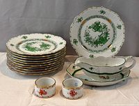 Group image showing 11 green plates, gravy boat with underplate, two red napkin rings