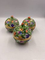 Three spherical Herend trinket boxes front view showing floral decoration and strawberry finials