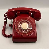 Front view of red Northern Electric rotary phone showing handset, dial, coiled cord