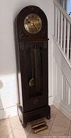full view of oak tall case clock with pendulum and two detached brass weights