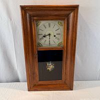 Front view of pine wall clock showing dial and painted glass panels
