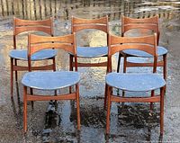 Front view of six teak dining chairs with blue seats