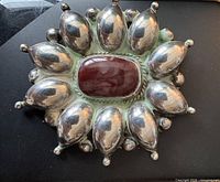 Front view showing silver pod design and central red cabochon