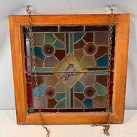 Front view of stained glass panel in wood frame with hanging chains visible