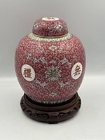 Front view of porcelain ginger jar on wood stand showing pattern and lid