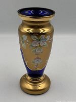 Full view of cobalt blue gilt glass vase showing enamel floral details and form