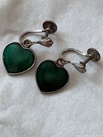 Front view of both green heart earrings showing enamel texture and overall design