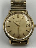 Close view of watch dial showing markers, hands, date window, brand and condition