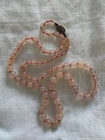 Full view of rose quartz bead necklace laid flat showing length and bead color