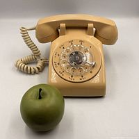Front view of beige rotary dial telephone with handset and coiled cord