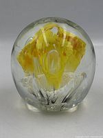 Front view of clear glass paperweight with yellow internal design