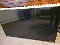 Front view of JVC flat screen television leaning against piano