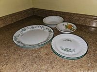 Stacks of dinner plates, salad plates, soup bowls, and floral dessert bowl