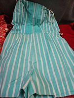 Front view turquoise and white striped romper laid flat