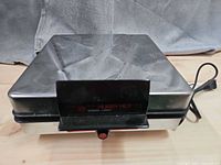 Closed waffle maker showing stainless housing and indicator light